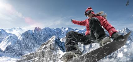 Close up image of female snowboarder making jump in snowy mountains